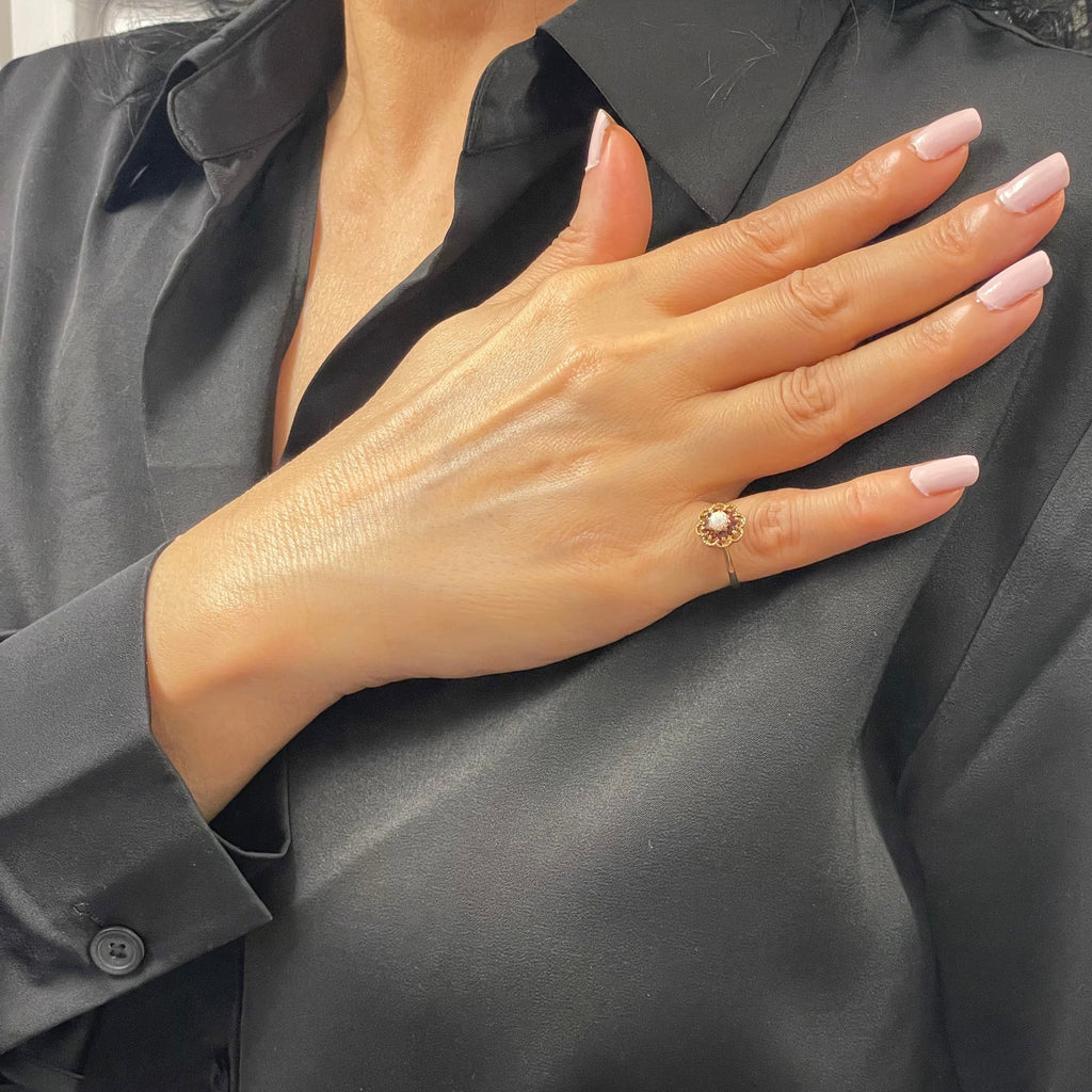 Lovely 14K yellow gold ring. A beautiful opal is set in the heart of the flower and 8 small garnets serve as petals in an openwork decor.