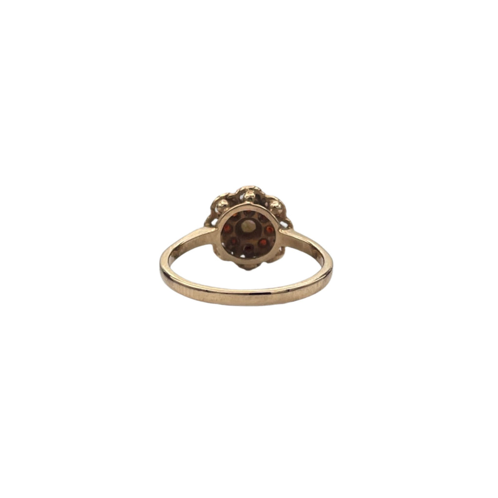 Lovely 14K yellow gold ring. A beautiful opal is set in the heart of the flower and 8 small garnets serve as petals in an openwork decor.